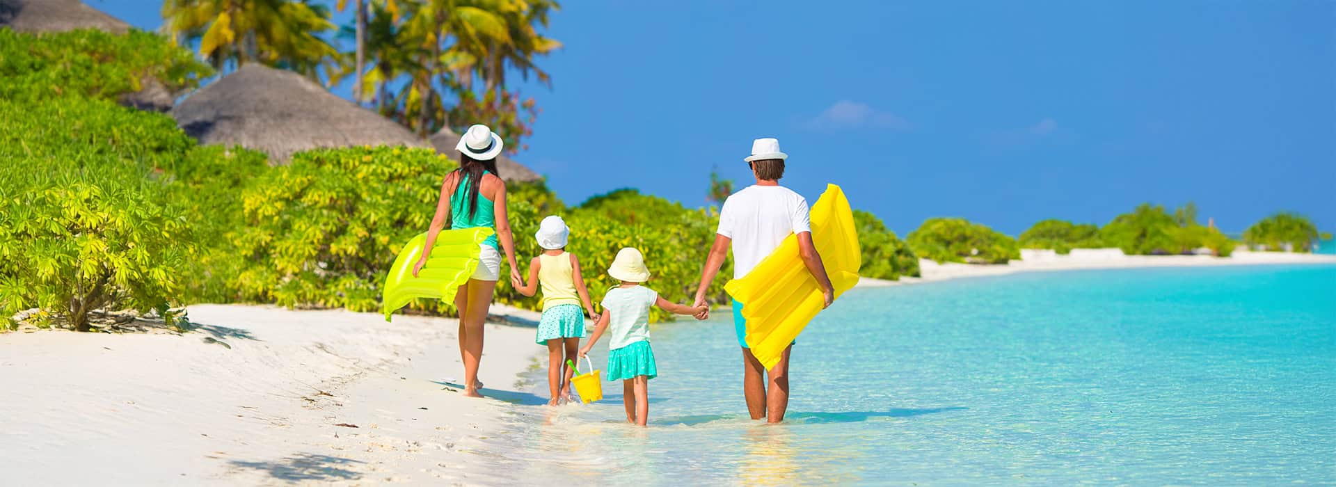 A family walking on the beach with surfboards.